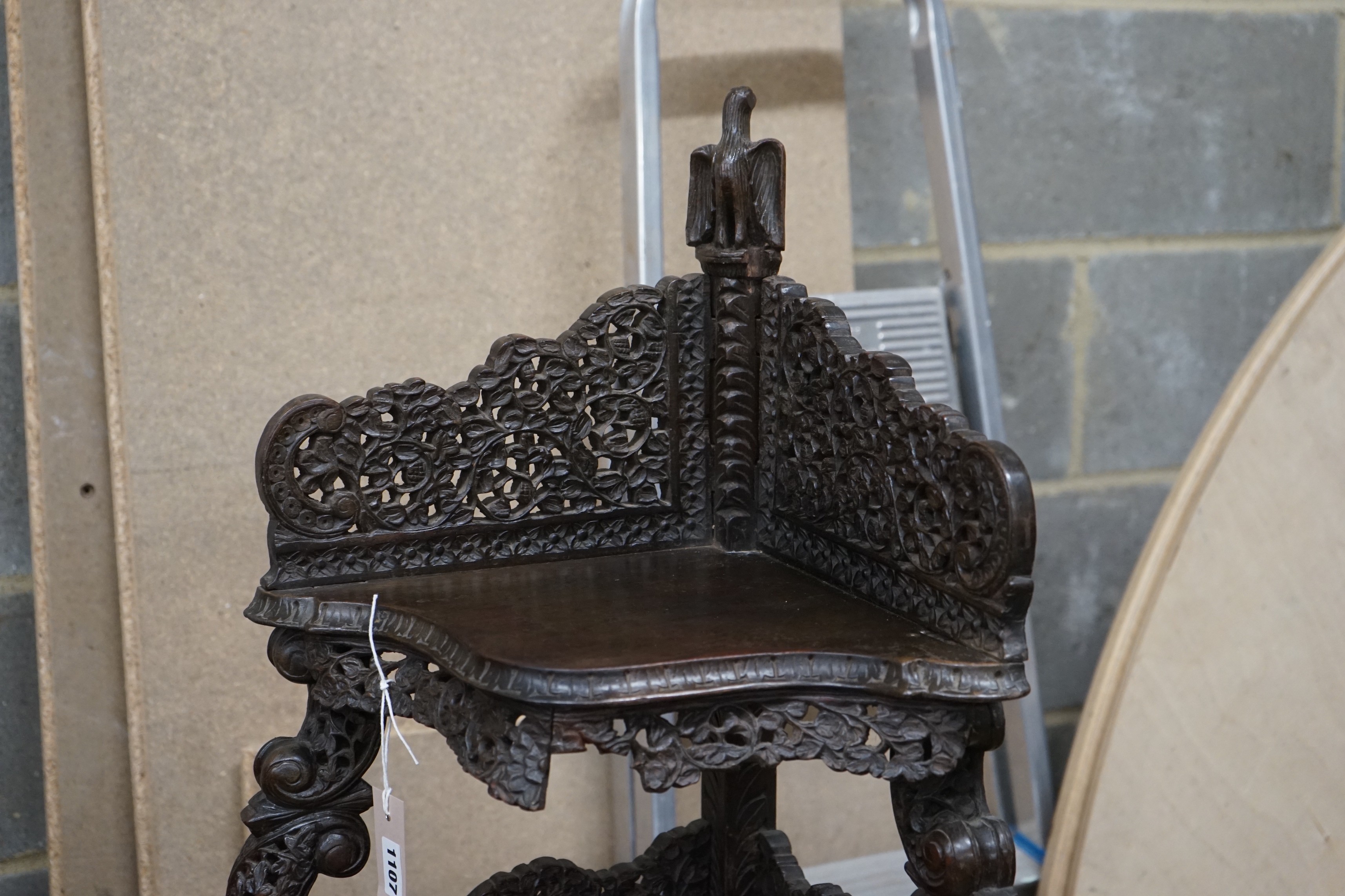 A 19th century Burmese carved hardwood serpentine corner whatnot, width 60cm, depth 42cm, height 153cm